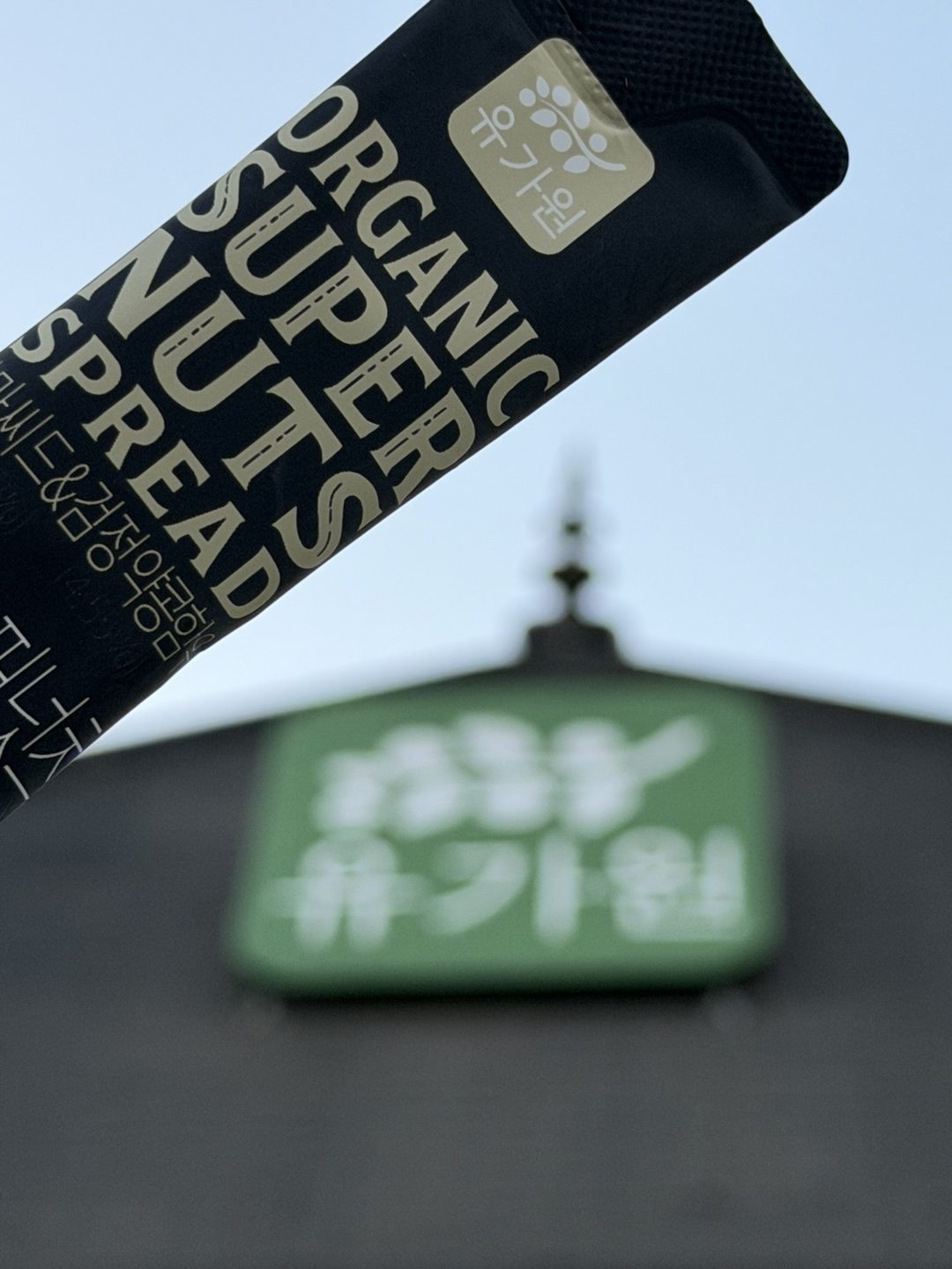 ORGANIC SUPER NUT SPREAD stick pack held in front of the YOUGAONE sign